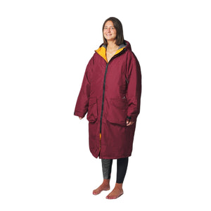 Person wearing a long burgundy coat with yellow lining on a white background